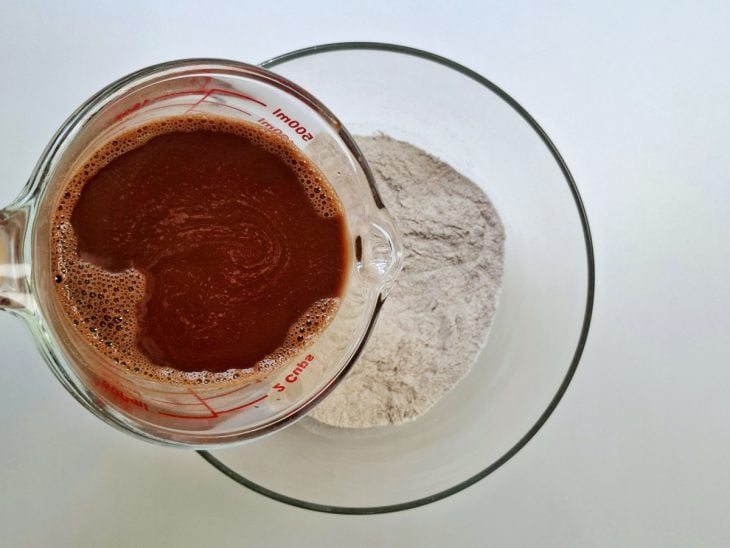 Ingredientes secos adicionados no recipiente e mistura de água e cacau para despejar.