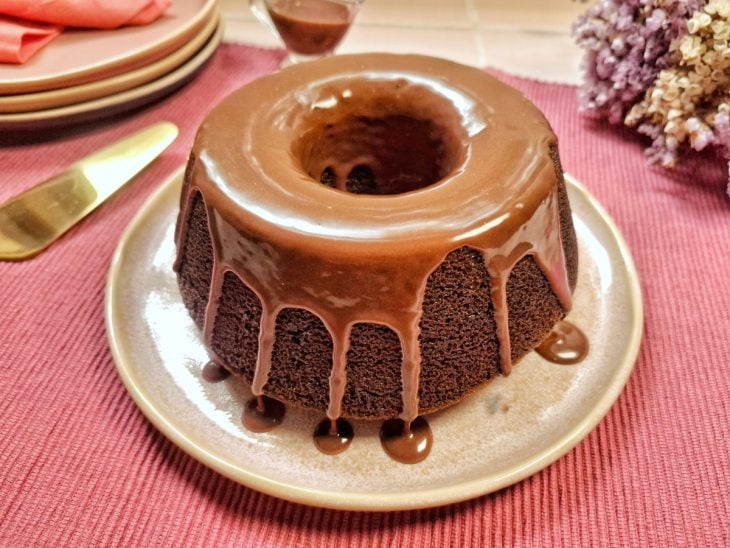 Bolo de chocolate sem ovo finalizado com calda de chocolate e pronto para servir.