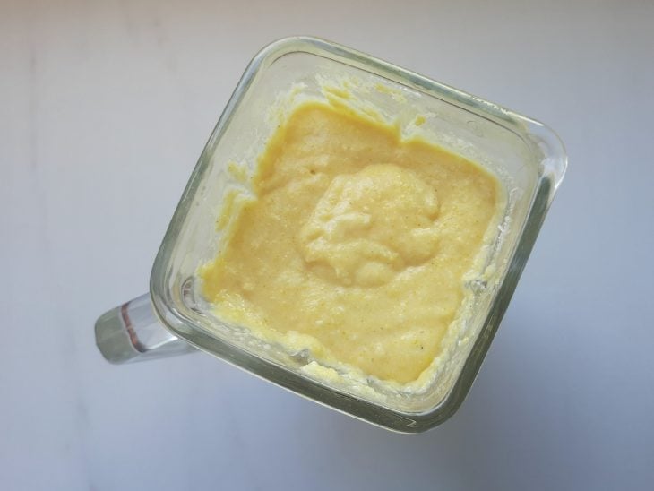 Um liquidificador contendo a mistura de ovos, açúcar, leite, óleo, farinha de milho, parmesão, coco ralado e fermento.
