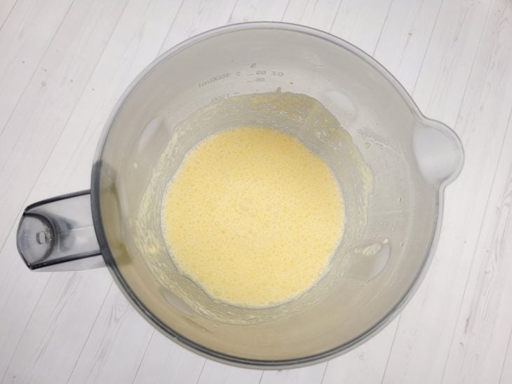 Um liquidificador contendo a mistura de ovos, açúcar, queijo ralado, manteiga, amido de milho, coco ralado, fubá e leite.