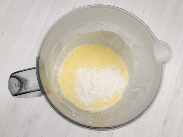 Um liquidificador contendo a mistura de ovos, açúcar, queijo ralado, manteiga, amido de milho, coco ralado, fubá, leite e fermento.