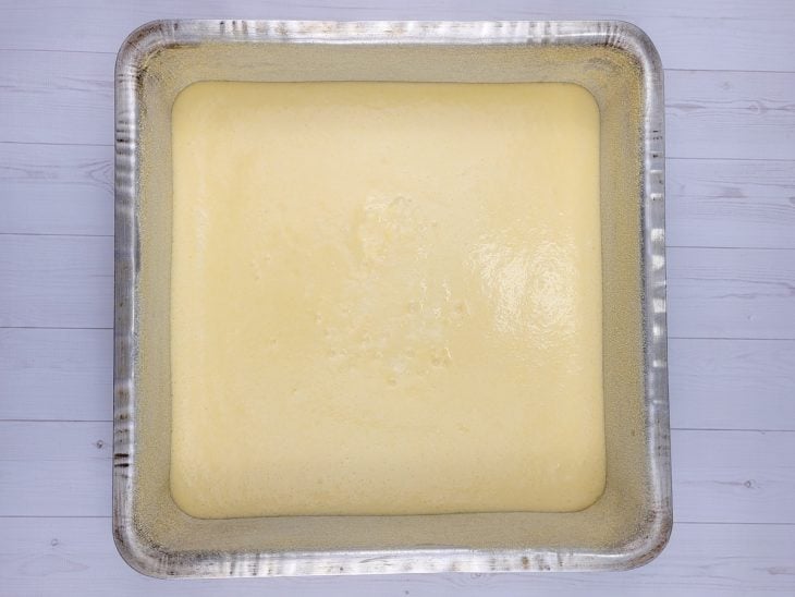 Uma forma contendo massa de bolo de fubá com queijo.