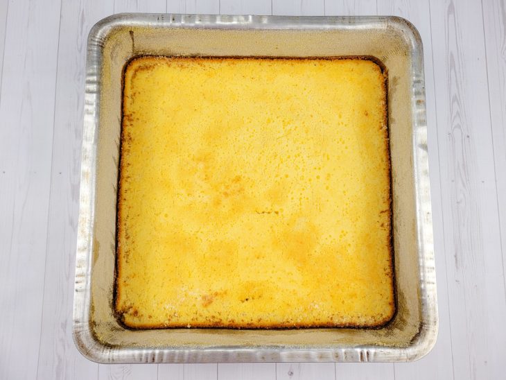 Uma forma contendo bolo de fubá com queijo.