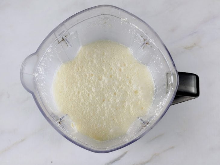 Leite integral, leite de coco, ovos, manteiga e queijo ralado batidos em um liquidificador.