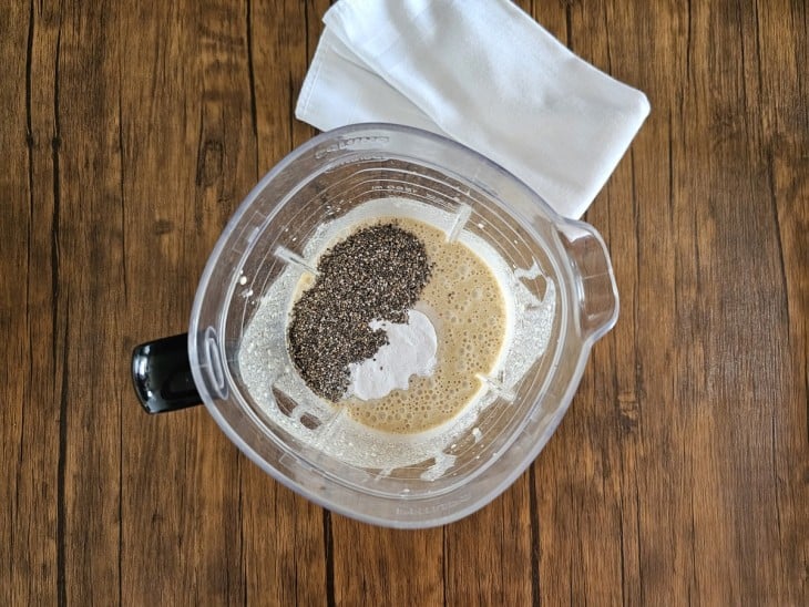 Um liquidificador contendo a mistura de leite de coco, ovos, óleo, coco ralado, adoçante, fubá, canela, chia e fermento.