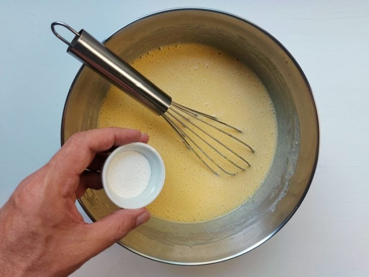 Um fouet e um recipiente contendo a massa crua do bolo de fubá sem farinha de trigo.