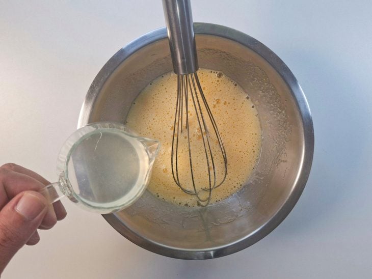 Água com limão sendo incorporada à massa aos poucos.