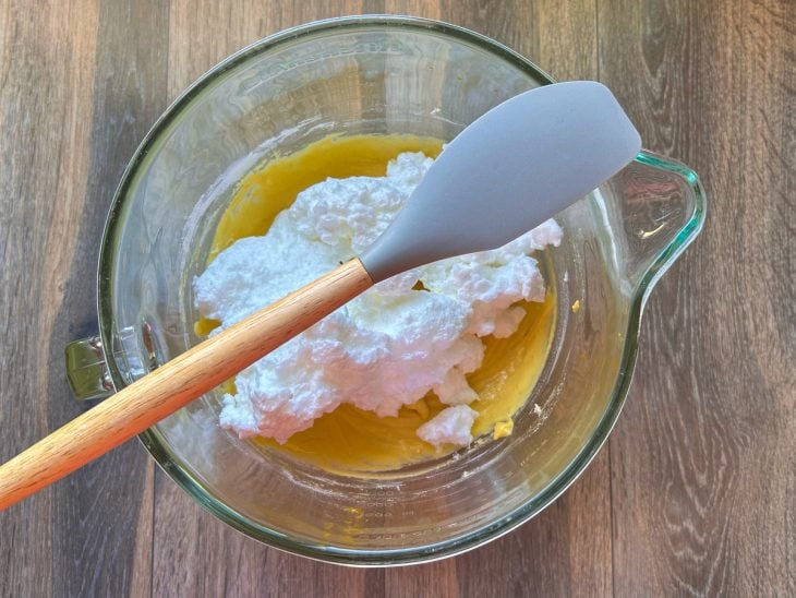 Claras em neve adicionadas na tigela com a mistura.