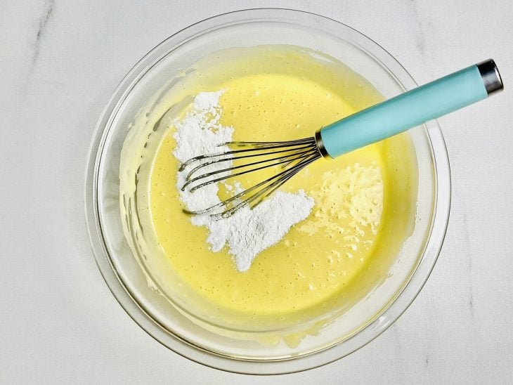Mistura do liquidificador em uma tigela de vidro junto com a farinha e o fermento em pó.