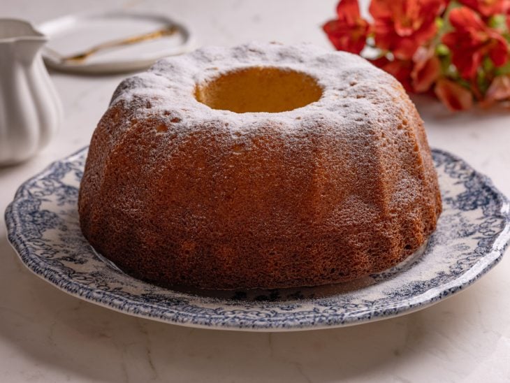 Bolo desenformado sobre um prato e finalizado com açúcar de confeiteiro.