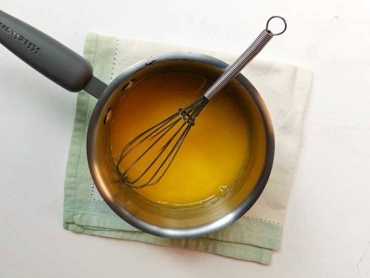 Calda do bolo de laranja em uma panela com fouet.