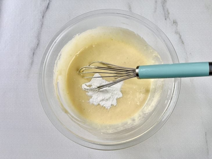 Farinha de trigo e fermento adicionados na tigela com a mistura peneirada.
