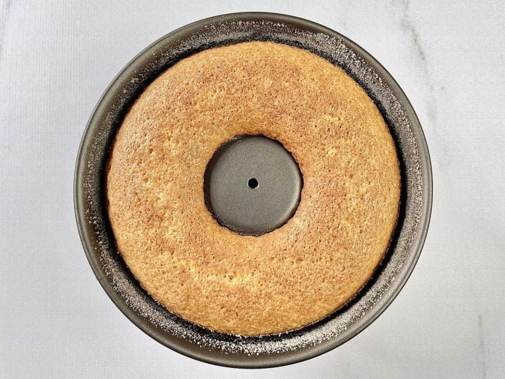 Bolo de laranja com casca simples assado em uma forma redonda com furo no meio.