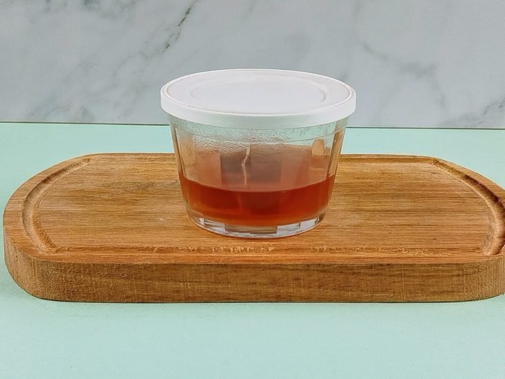 Chá infusionado em um recipiente pequeno de vidro com tampa.