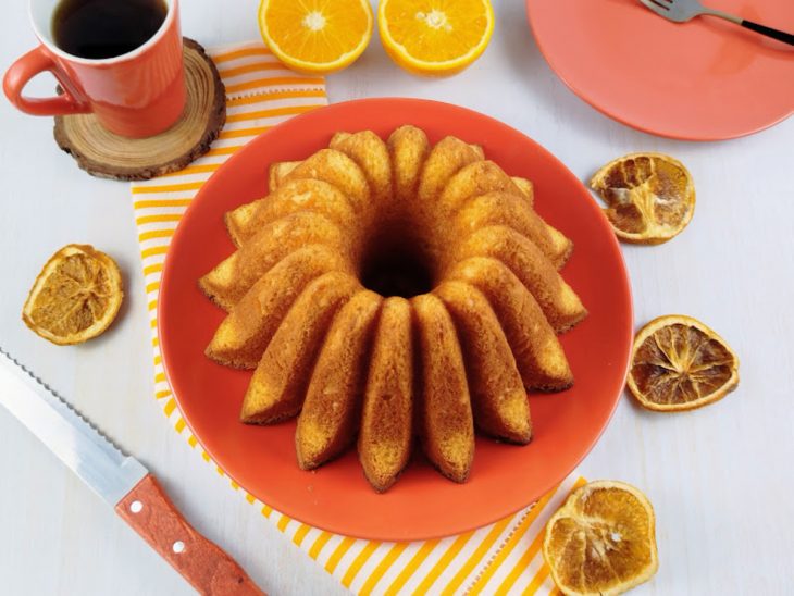 Bolo de laranja pronto para consumo sobre uma boleira.
