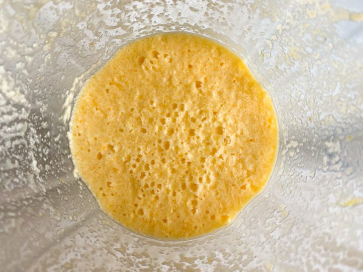 No liquidificador, a massa após o acréscimo das raspas e o suco da laranja.