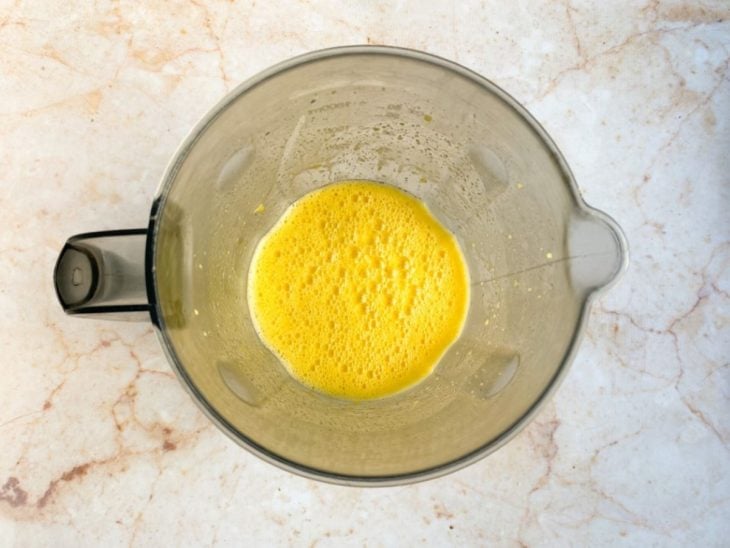 Um liquidificador com ovos, açúcar, suco de laranja e óleo batidos.