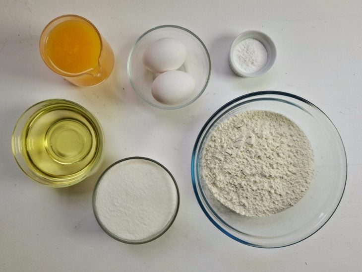 Todos os ingredientes necessários para fazer o bolo de laranja simples em uma bancada.