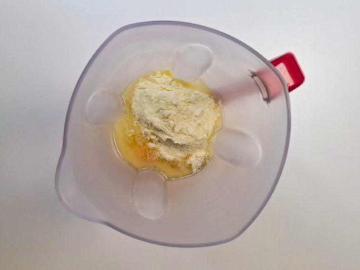 Ovos, açúcar, óleo, leite e leite em pó misturados em um liquidificador.