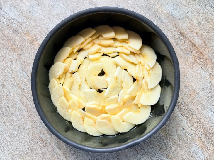 Fatias de maçã sobre o caramelo na forma.