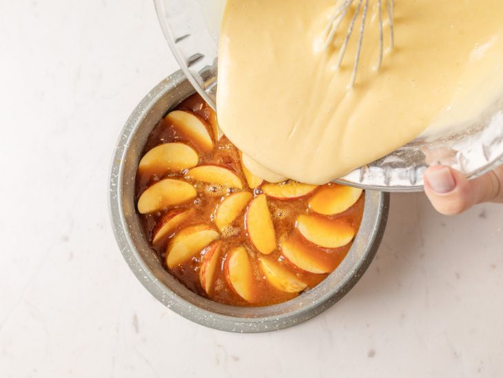 Massa despejada sobre a forma com o caramelo e maçãs.