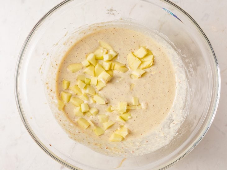 Maçã picada, farinha de trigo e fermento adicionados a tigela de vidro.