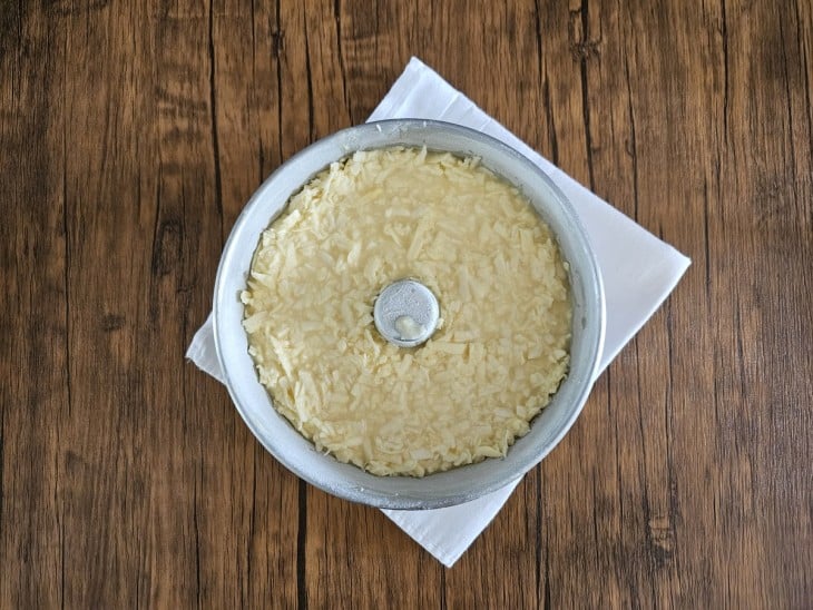Forma redonda com furo no meio com massa de bolo de mandioca com coco crua.