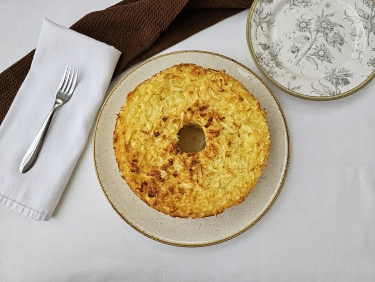 Bolo de mandioca com coco em formato redondo.