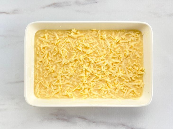 Um refratário contendo massa crua de bolo de mandioca crua.