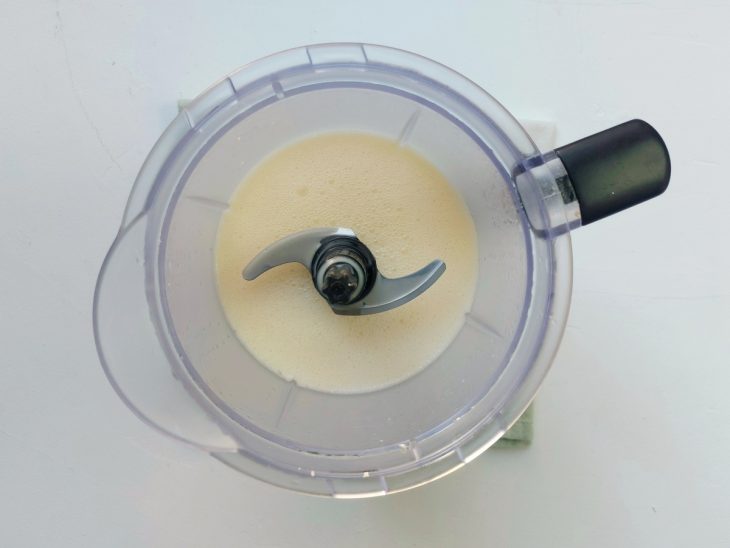 Um liquidificador com ovos, óleo de coco, açúcar, leite de coco, água e sal.