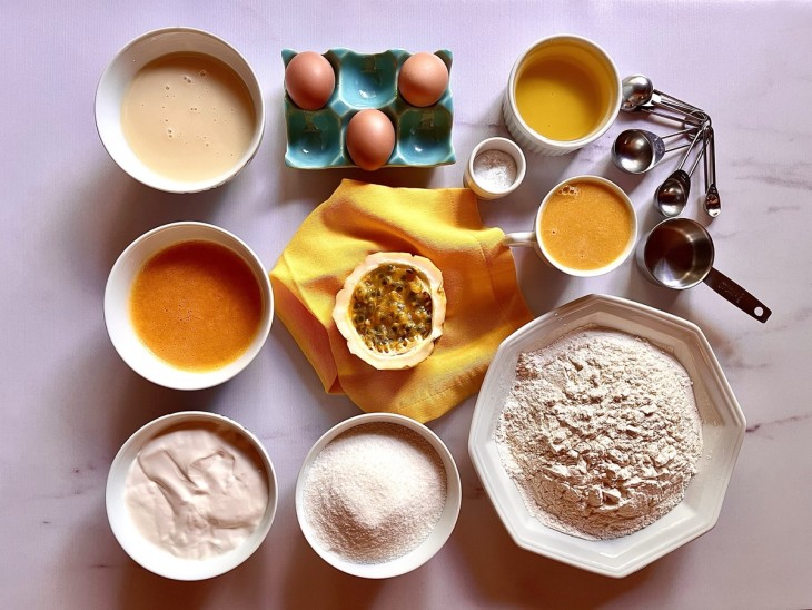 Ingredientes reunidos em recipientes distintos: ovos, farinha, fermento, óleo, maracujá, polpa do maracujá, creme de leite, leite condensado e açúcar.