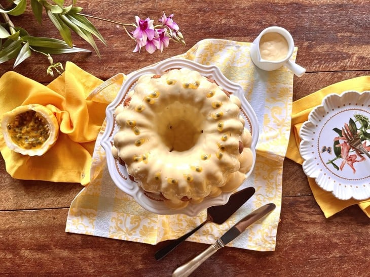 Bolo de maracujá pronto com a cobertura de maracujá e sementes da fruta decorando por cima.