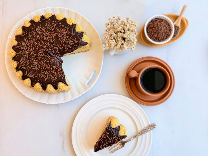 Bolo pronto, pedaço servido em prato, com café.