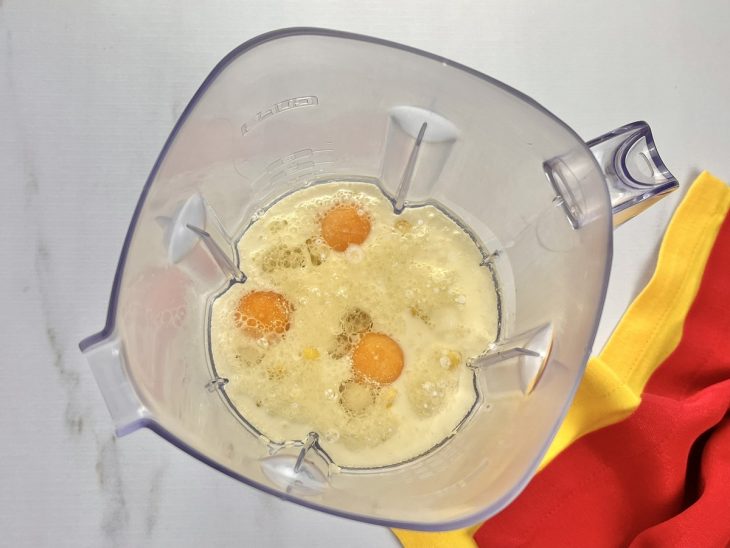 Um liquidificador com ovos, açúcar, sal, leite, milho e óleo.