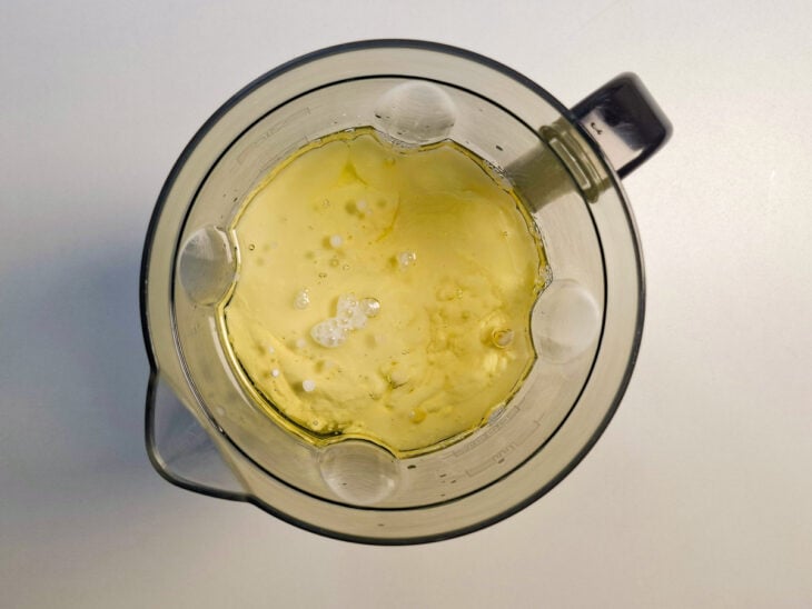 Ovos, óleo, leites, milho, fubá e coco sendo despejados juntos no copo do liquidificador.