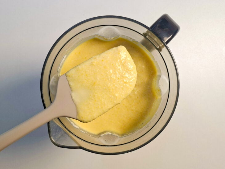 Liquidificador tampado batendo a mistura amarela até que fique completamente lisa e fluida.