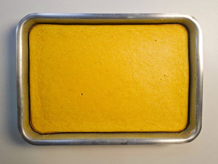 Bolo de milho assado, com superfície bem dourada e bordas coradas dentro da forma.