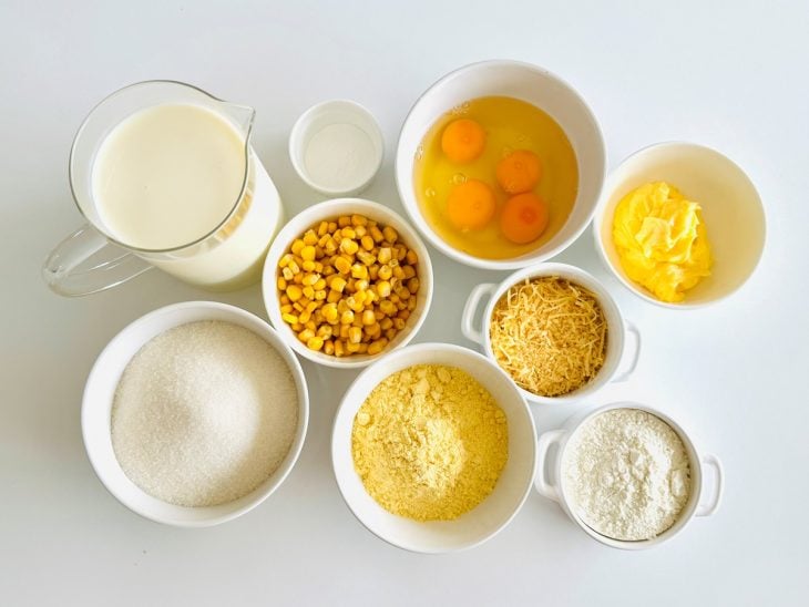 Ingredientes organizados na bancada com ovos já quebrados e milho escorrido.