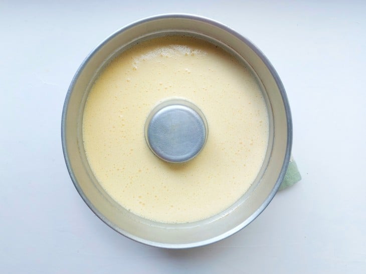 Massa do bolo de milho crua disposta em uma forma redonda com um furo no meio.