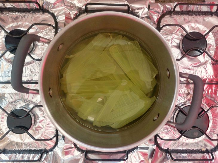 Uma panela com água e folhas de milho ao fogo.