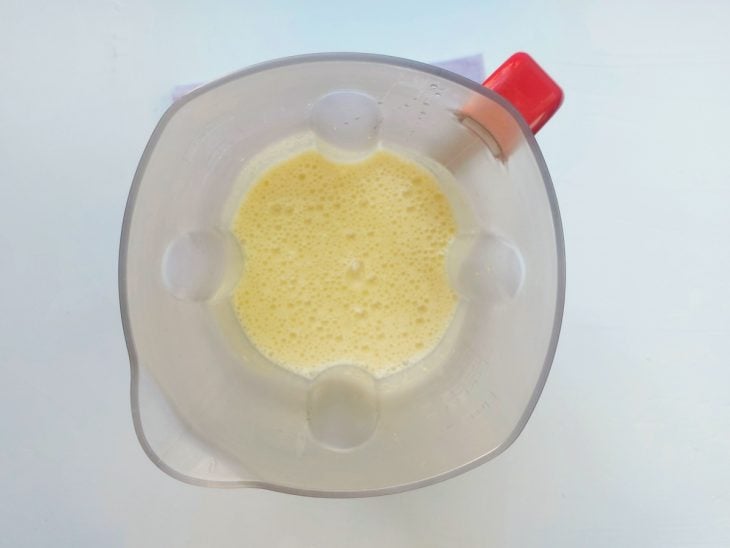 Um liquidificador com óleo, ovos, açúcar, leite de coco e milho.