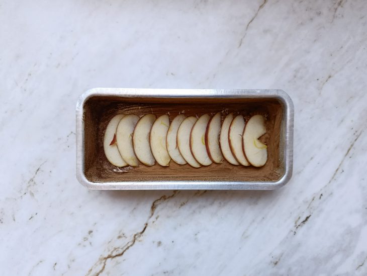 Forma untada e fatias de maçã dispostas nela.