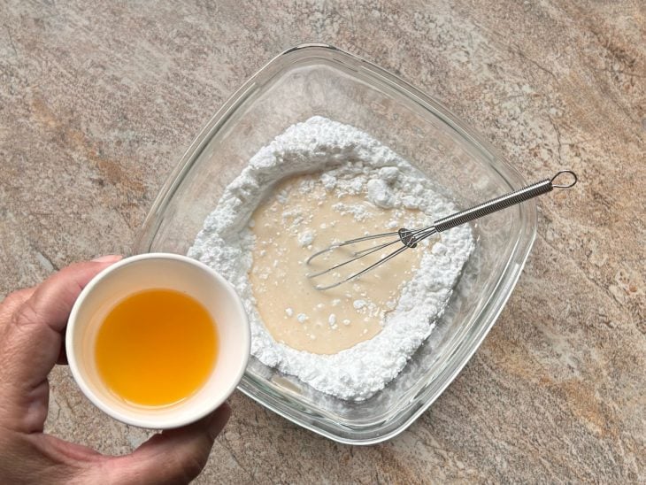 Leite, açúcar de confeiteiro e suco de ponkan misturados em uma tigela.