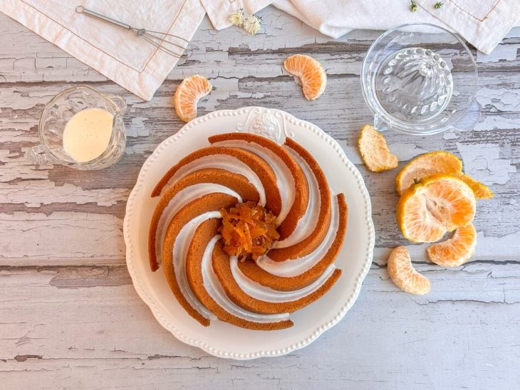 Bolo de ponkan com glacê pronto para consumo sobre uma boleira.