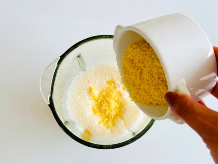 Queijo parmesão ralado sendo adicionado no liquidificador.