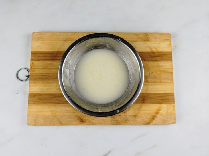 Açúcar de confeiteiro misturado com suco de limão em um tigela redonda pequena.