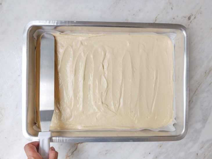 Massa acomodada numa assadeira com papel-manteiga.