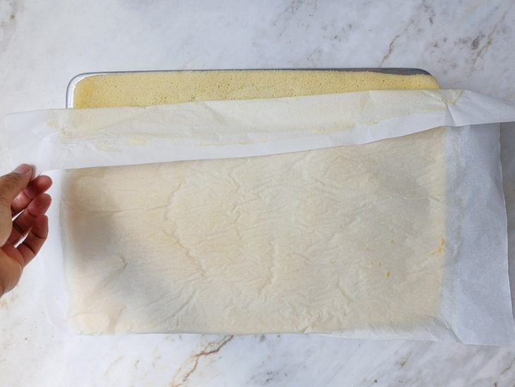 Papel-manteiga sendo retirado da base da massa desenformada.