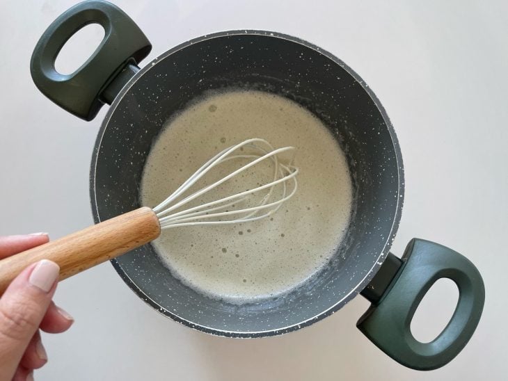 Mistura de claras e açúcar sendo aquecida levemente na panela.