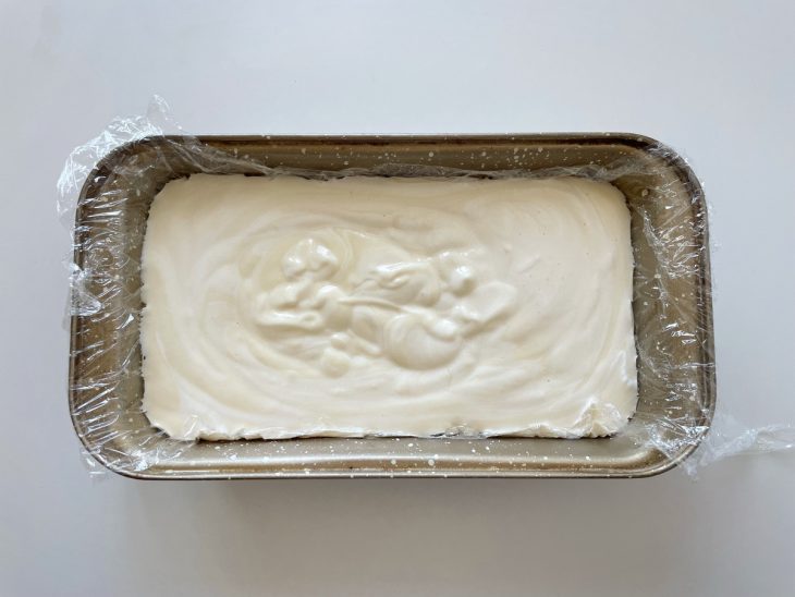 Forma forrada com plástico sendo preenchida com a mistura cremosa.